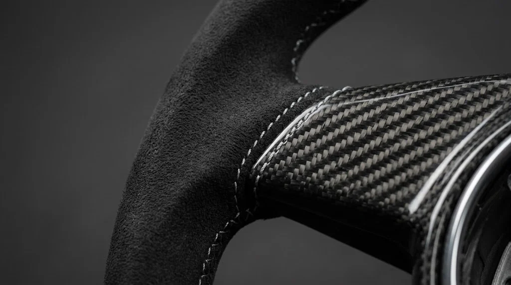 Close-up of the genuine Alcantara grip, carbon fiber weave and contrast stitching on a custom Porsche Panamera steering wheel